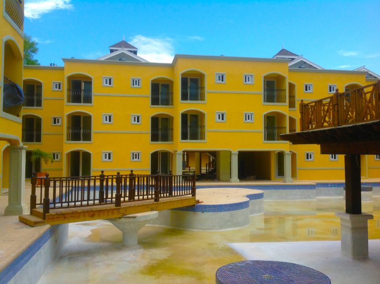 A yellow building with a bridge in front of it.