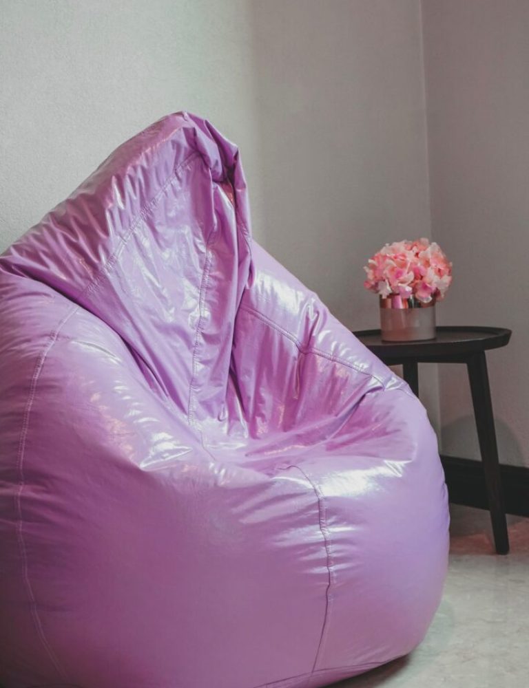 A purple bean bag chair in front of a wall.